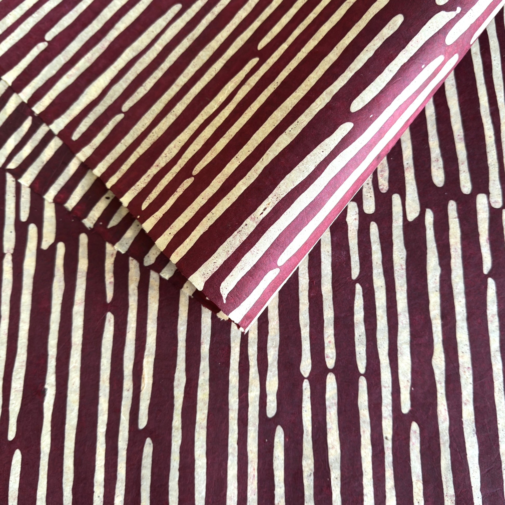 Nepalese handmade decorative lokta paper sheet with a stripe pattern in burgundy and white.  Batik dyed using carved wooden blocks. 