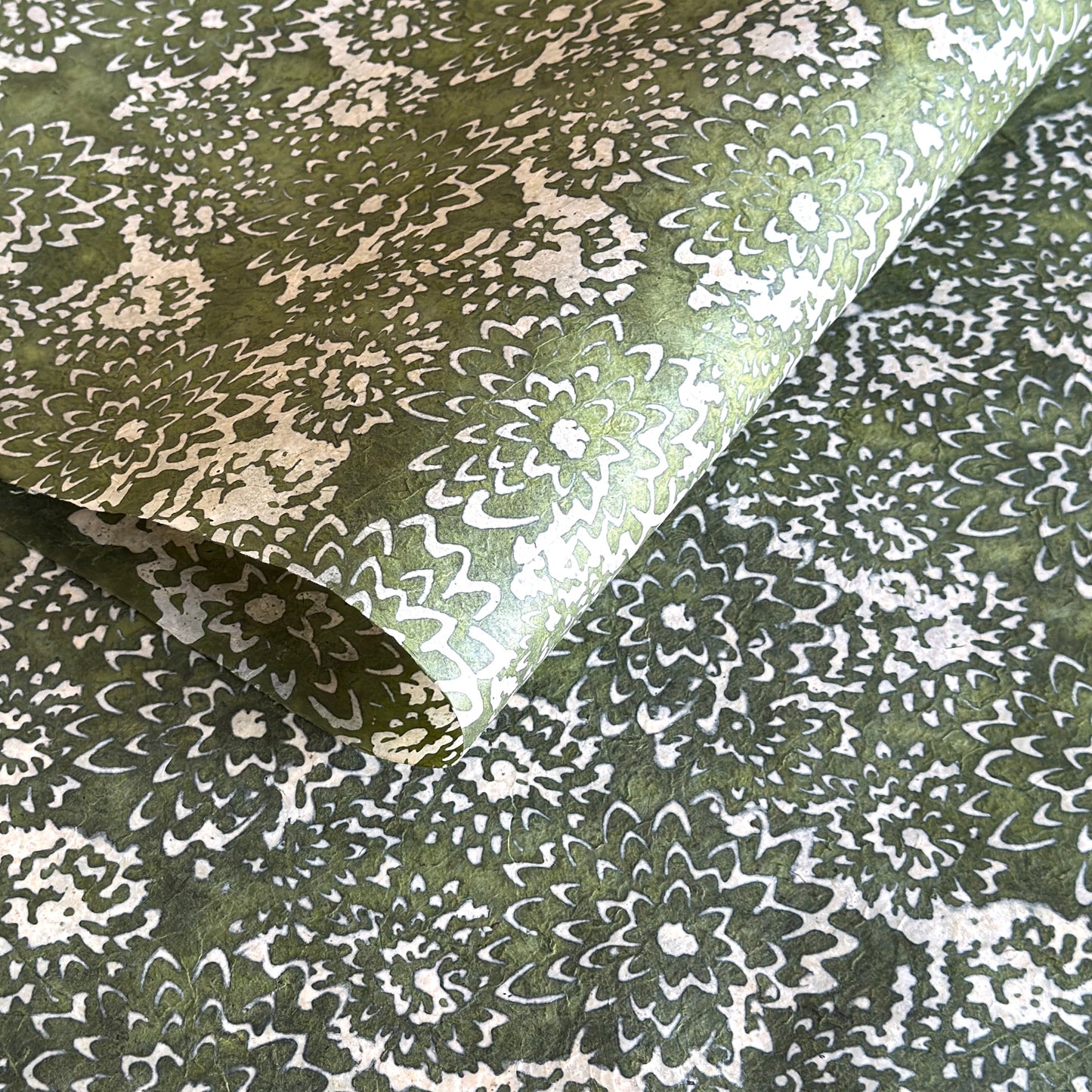 Nepalese handmade decorative lokta paper sheet with a floral pattern in green and cream.  Batik dyed using carved wooden blocks.