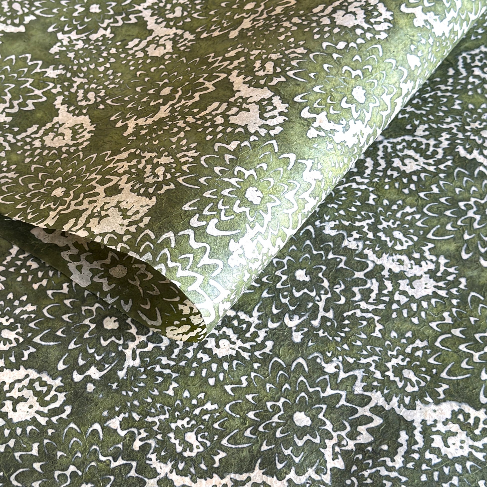 Nepalese handmade decorative lokta paper sheet with a floral pattern in green and cream.  Batik dyed using carved wooden blocks.
