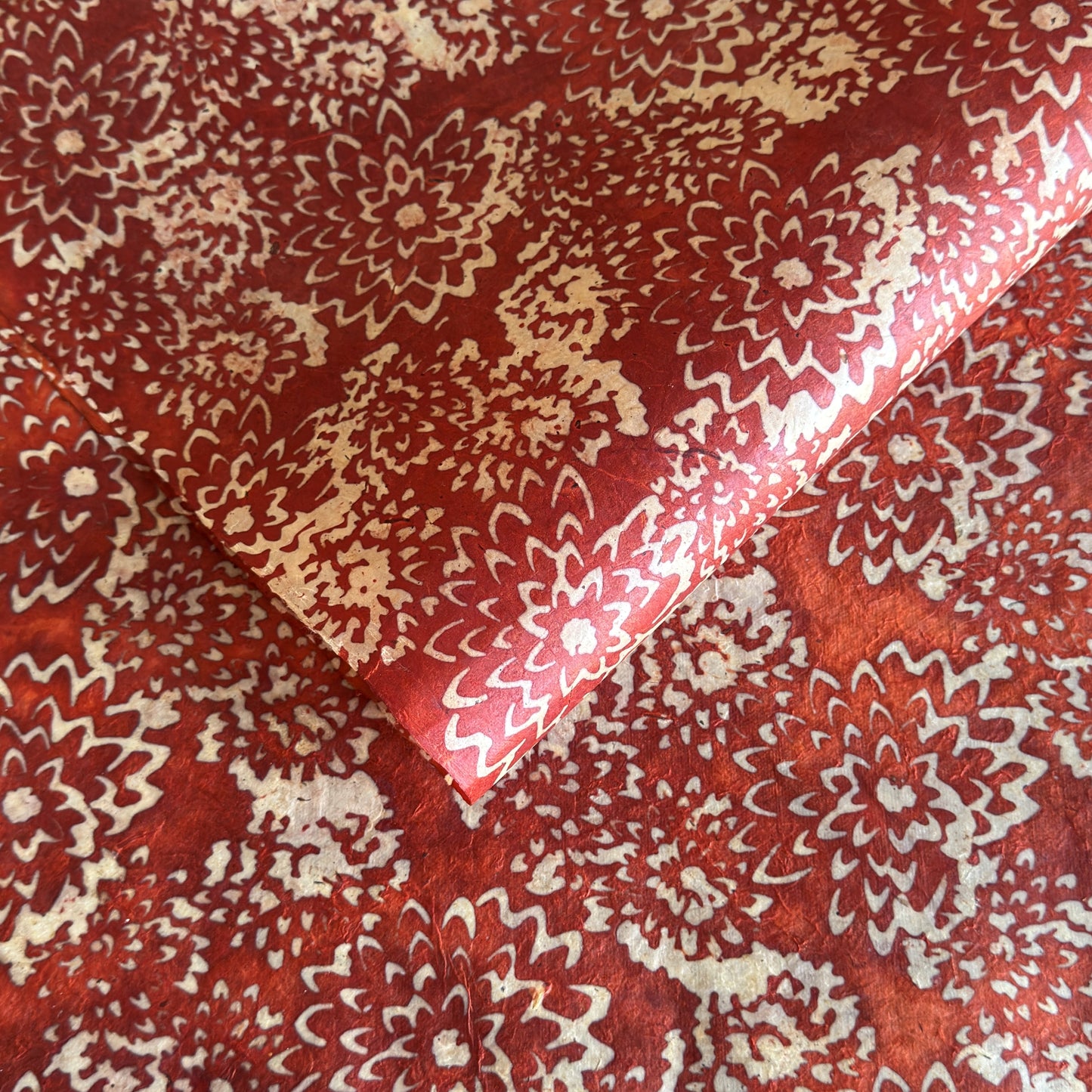 Nepalese handmade decorative lokta paper sheet with a floral pattern in rust and cream.  Batik dyed using carved wooden blocks.
