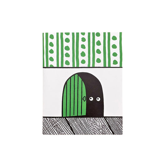 Small greetings card of a semi-circle green door in the skirting board, the door is slightly open showing two eyes of the mouse that lives there.  Above the skirting is green and white stripe/dot wallpaper by Lisa Jones Studio