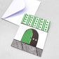 Small greetings card of a semi-circle green door in the skirting board, the door is slightly open showing two eyes of the mouse that lives there. Above the skirting is green and white stripe/dot wallpaper by Lisa Jones Studio