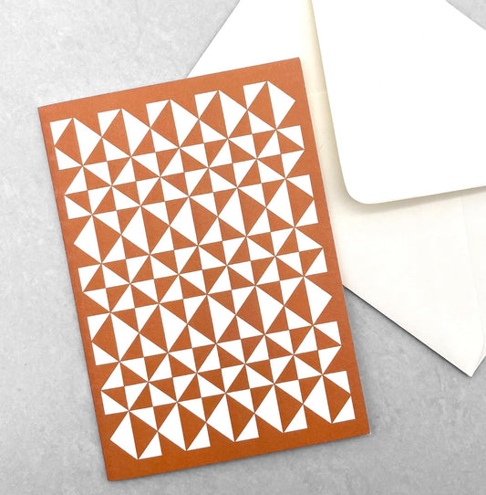 greetings card with abstract triangular pattern in white and brick red by Ola Studio, with white envelope
