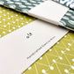 Slimline, softcover exercise book by Ola Studio with a triangular geometric cover in mustard and white, pictured with branded presentation band, close-up