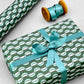 wavy striped geometric wrapping paper in forest green, aqua and white, by Ola Studio forest, wrapped present with ribbon bow