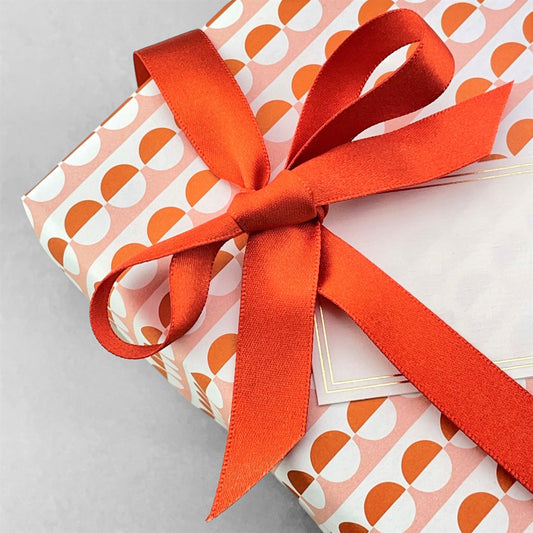 Luxury rust-orange satin ribbon on a rectangular board by Ola Studio, shown as a bow