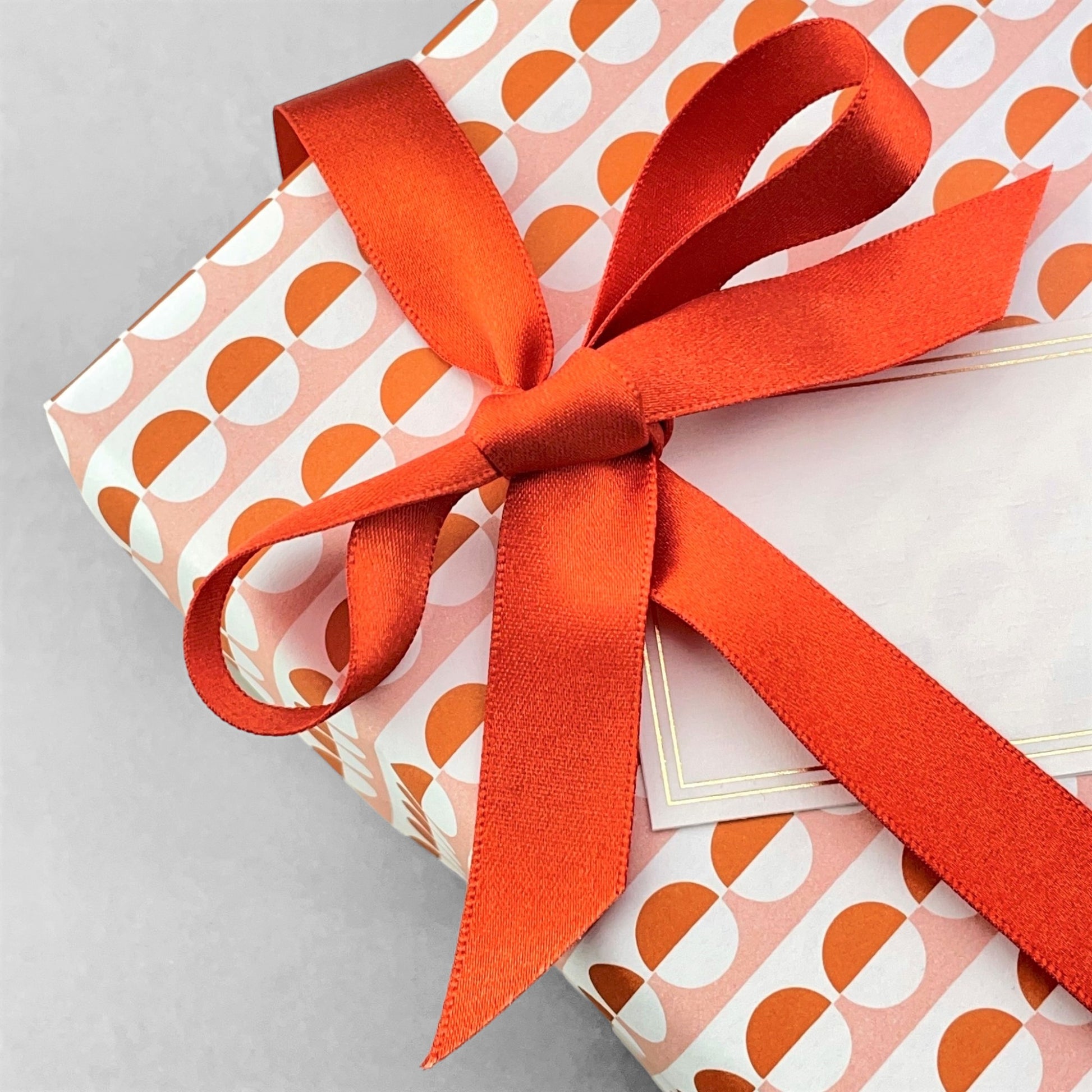 wrapping paper with an abstract circle pattern in orange and pale pink by Ola Studio