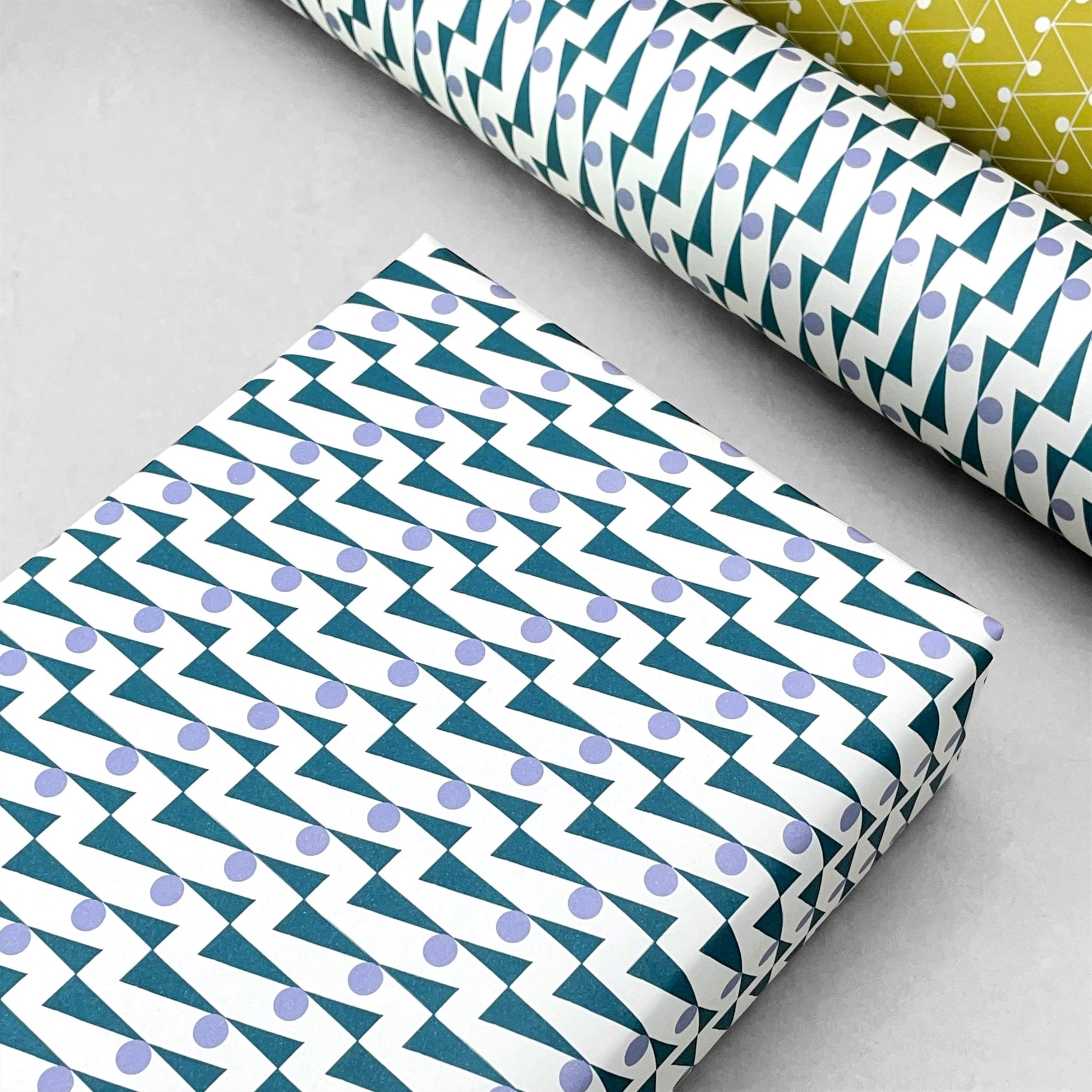 wrapping paper with abstract triangle and dot pattern in blue and lilac by Ola Studio