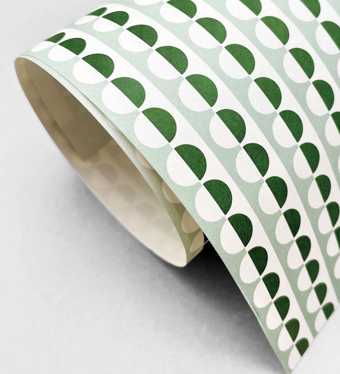 wrapping paper with an abstract circle pattern in dark green and pale green by Ola Studio