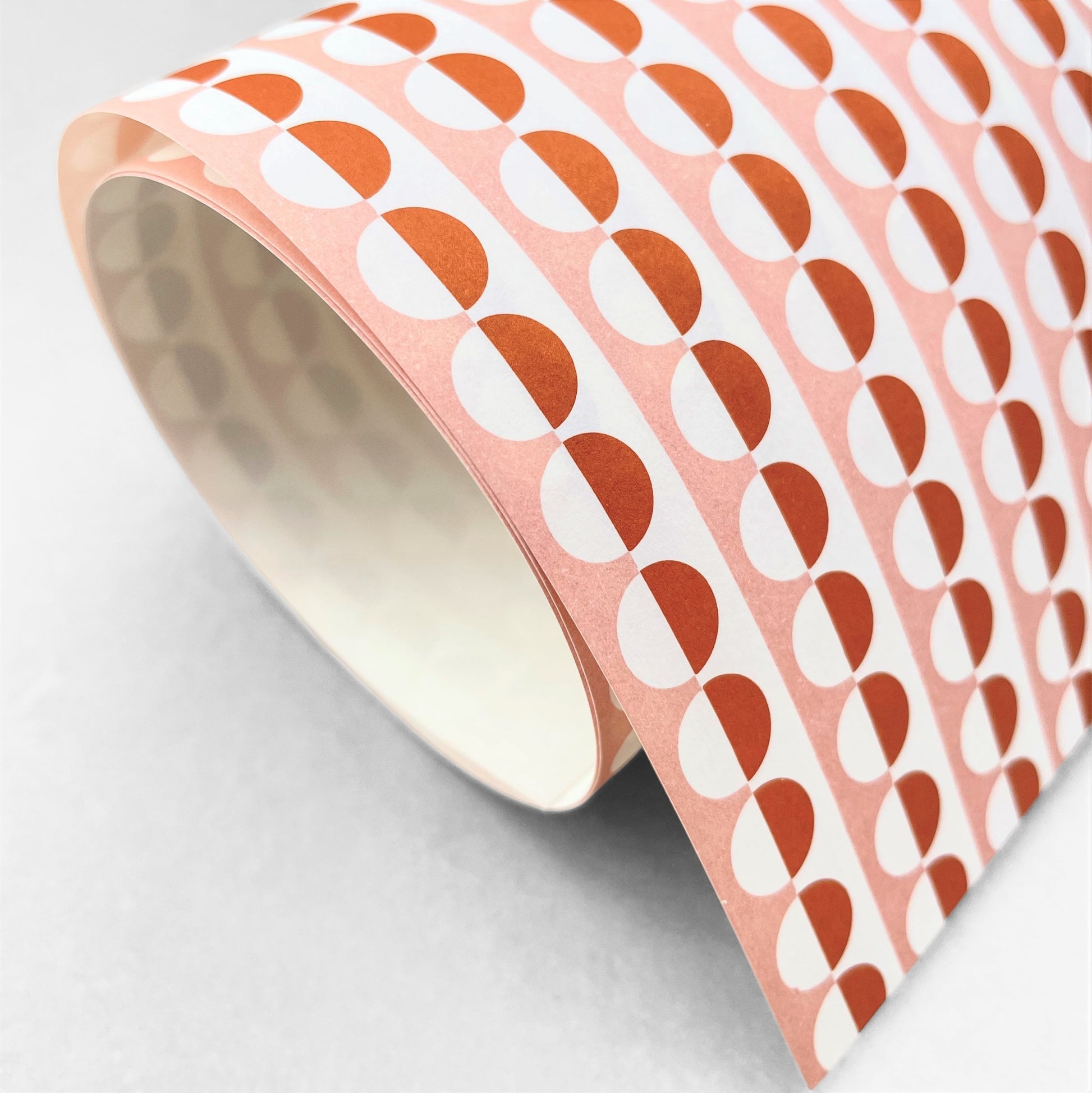 wrapping paper with an abstract circle pattern in orange and pale pink by Ola Studio
