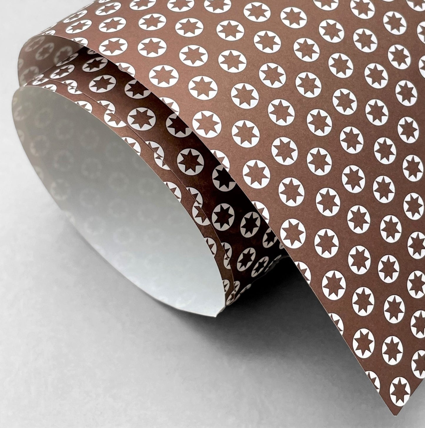 wrapping paper with an abstract tiny stars pattern in chestnut brown and white by Ola Studio