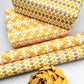 wrapping paper by Otto Editions with a cut-out palm design in white on a saffron yellow background. Pictured wrapped as a present with other designs