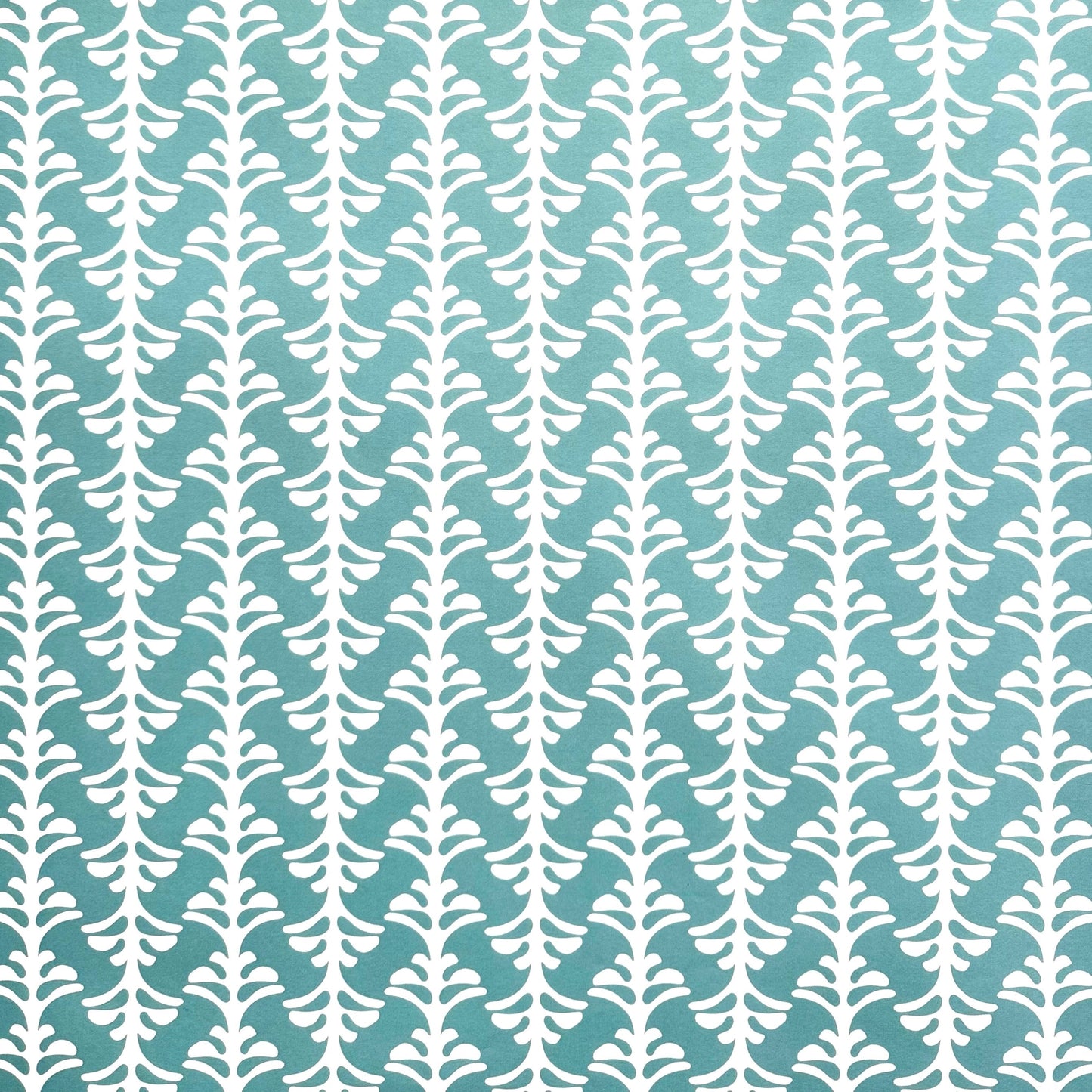 wrapping paper by Otto Editions with a cut-out palm design in white on an aqua blue background. 