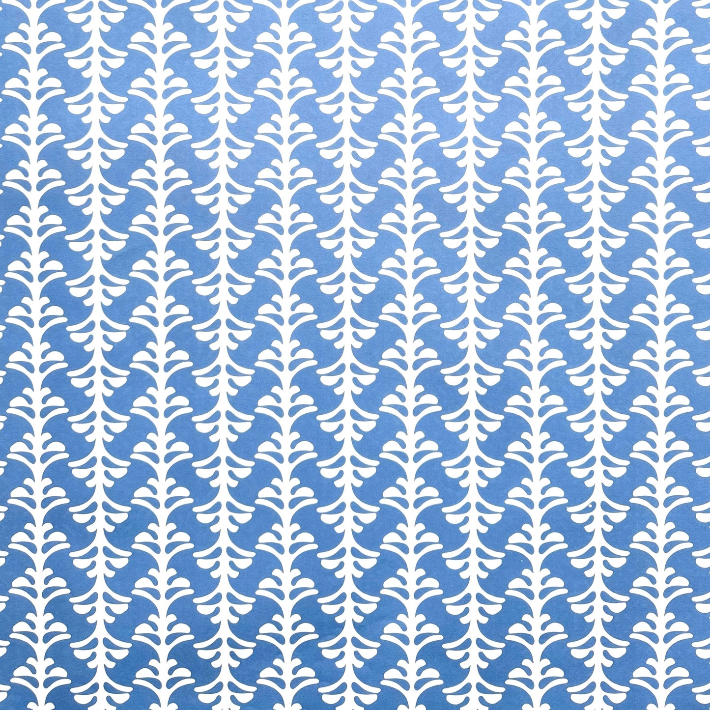 wrapping paper by Otto Editions with a cut-out palm design in white on a sky blue background. 
