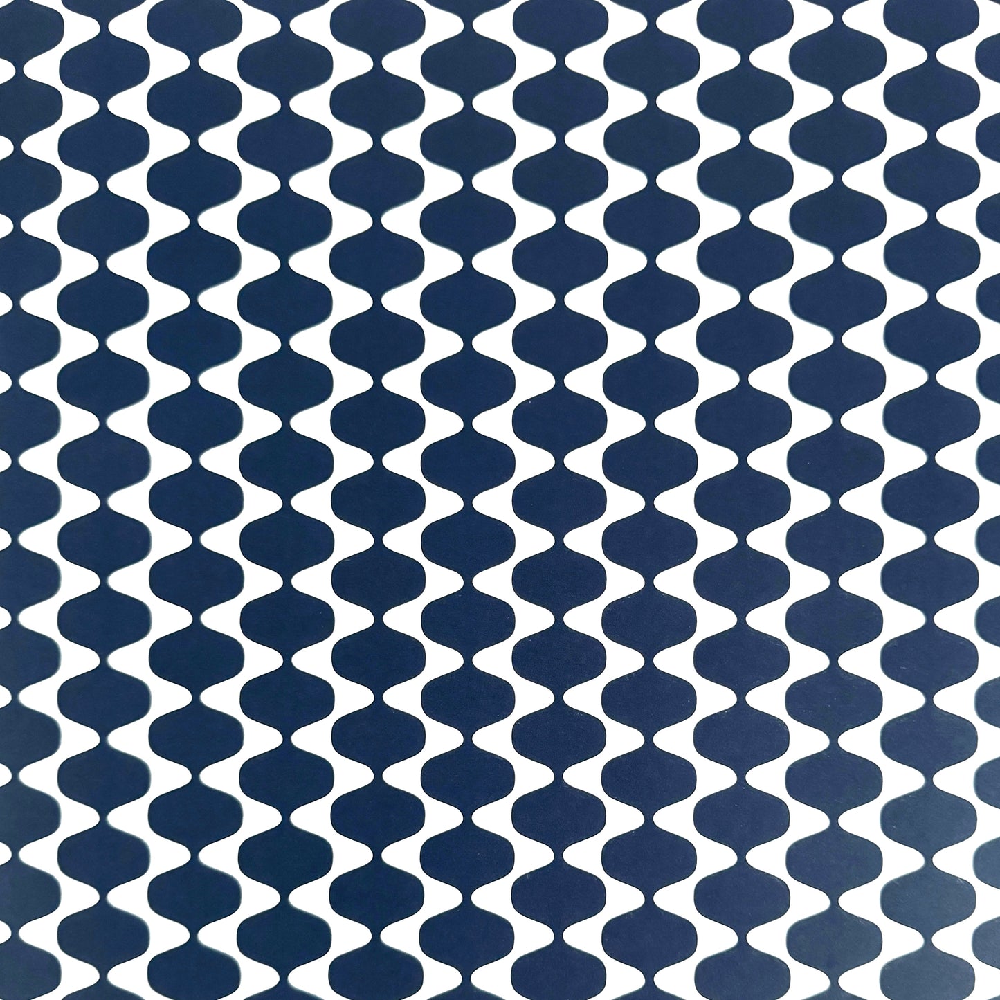 wrapping paper by Otto Editions with a cut-out wavy design in white on an indigo background. 