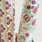 Hand block printed wrapping paper with a trellis pattern with flowers in cherry red, green and gold. close up