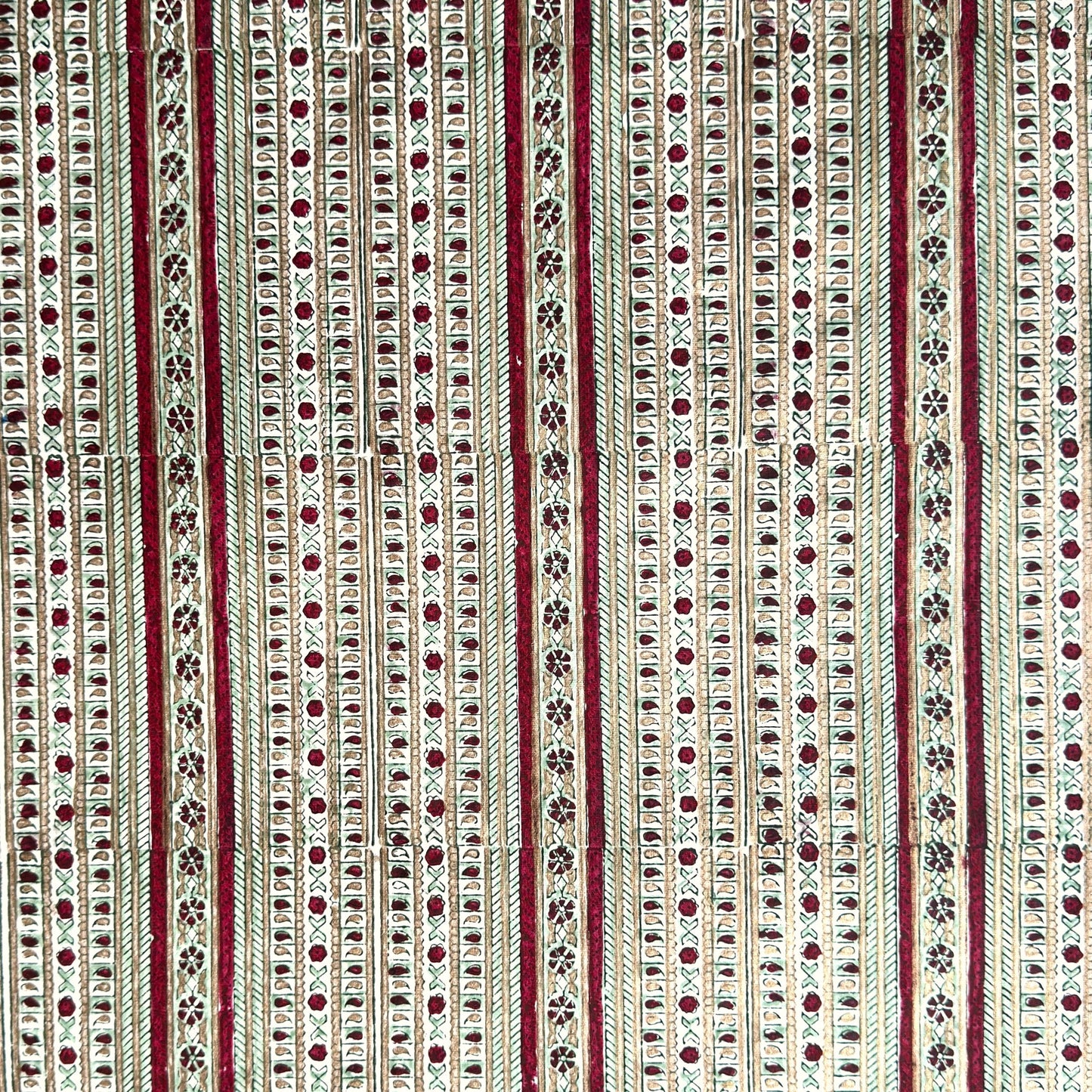 Hand block printed wrapping paper with a striped design in red, green and gold. 