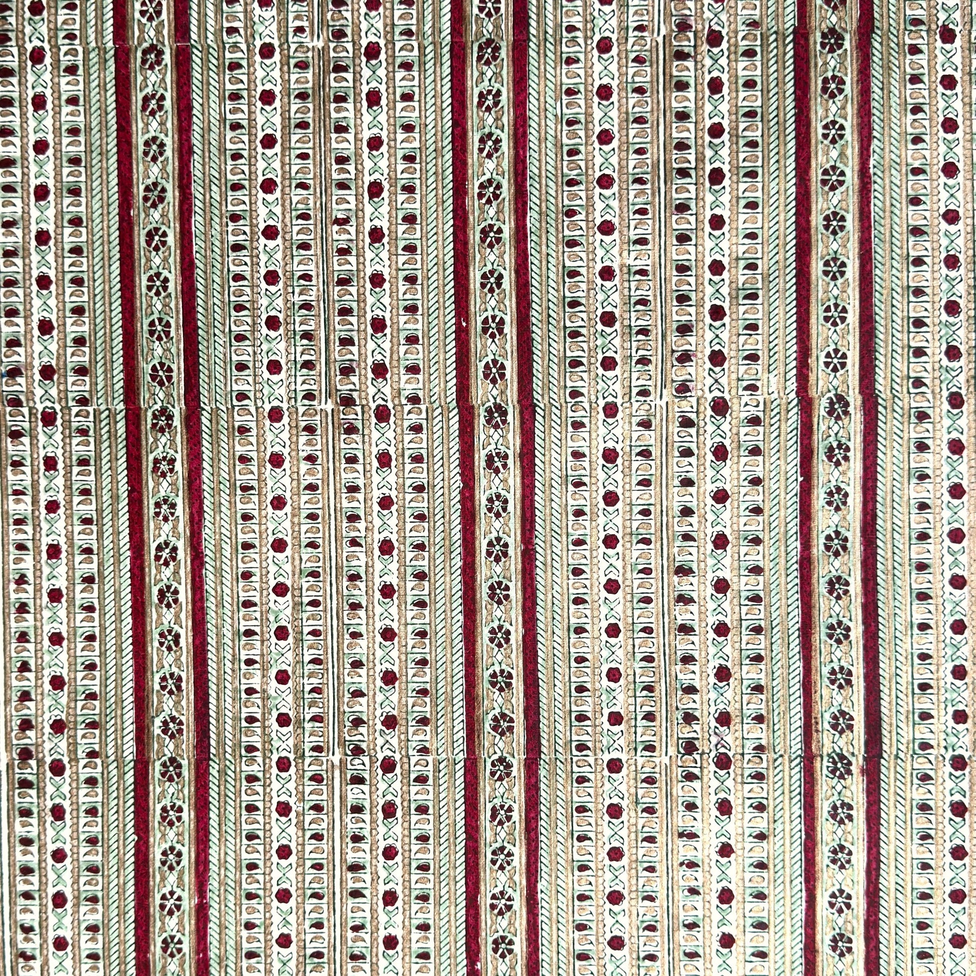 Hand block printed wrapping paper with a striped design in red, green and gold. 