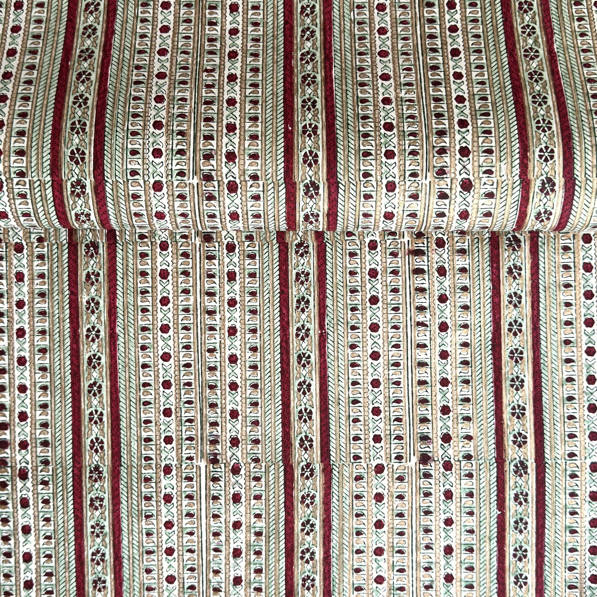 Hand block printed wrapping paper with a striped design in red, green and gold. 