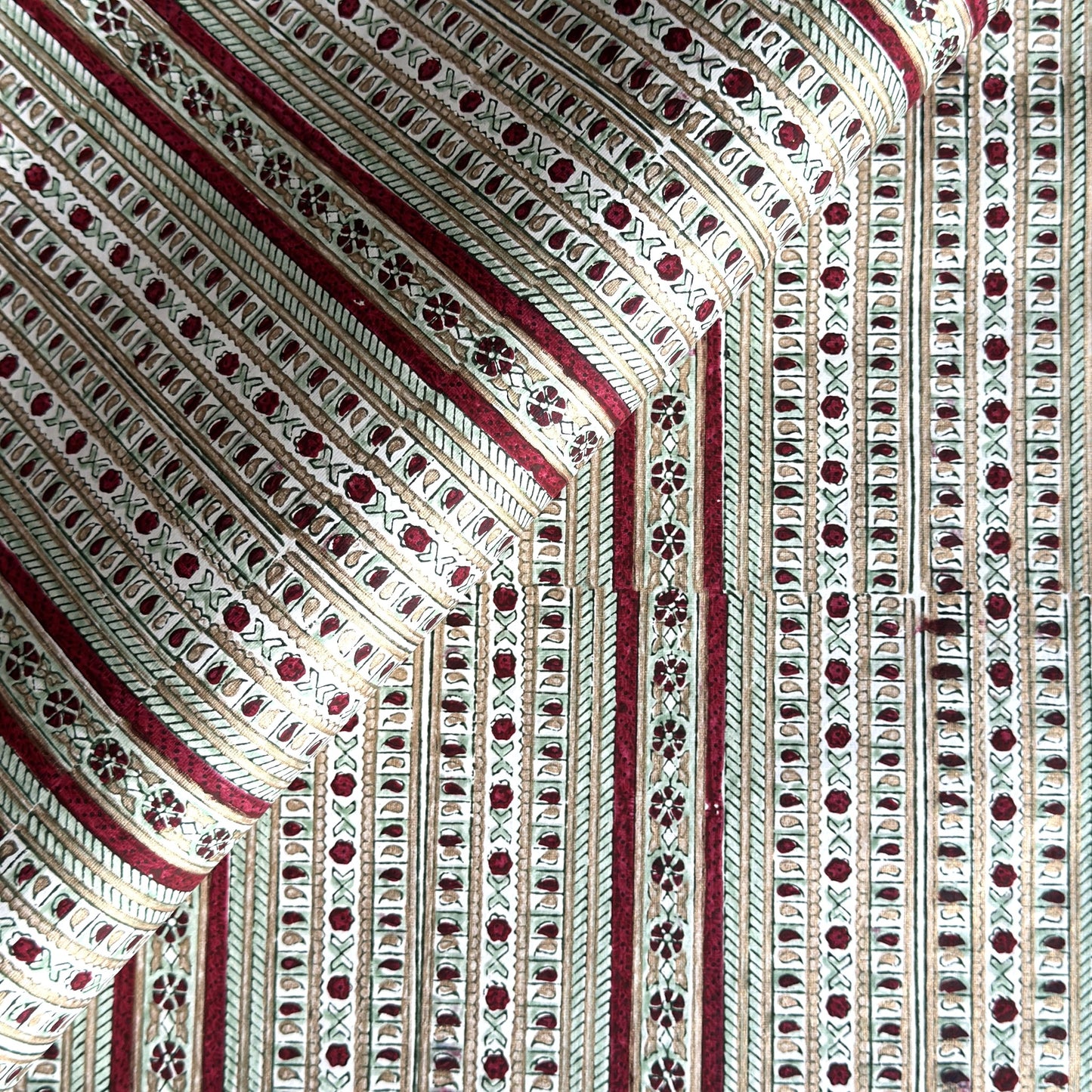 Hand block printed wrapping paper with a striped design in red, green and gold. 
