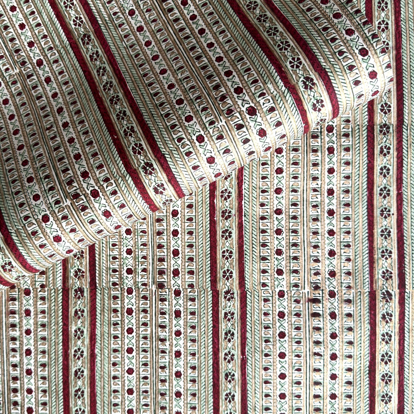 Hand block printed wrapping paper with a striped design in red, green and gold. 