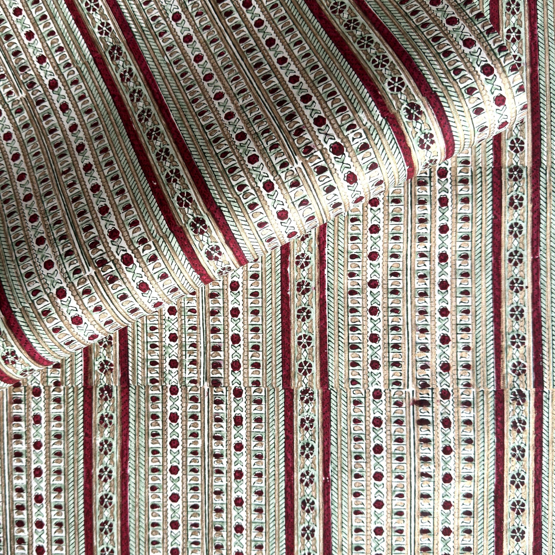 Hand block printed wrapping paper with a striped design in red, green and gold. 