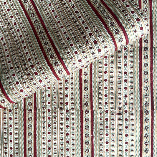 Hand block printed wrapping paper with a striped design in red, green and gold. 