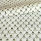 a sheet of hand block printed paper with a pattern of green bows on white