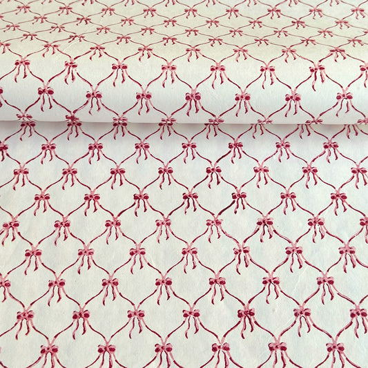 a sheet of hand block printed paper with a red and pink bow design on white
