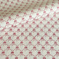 a sheet of hand block printed paper with a red and pink bow design on white