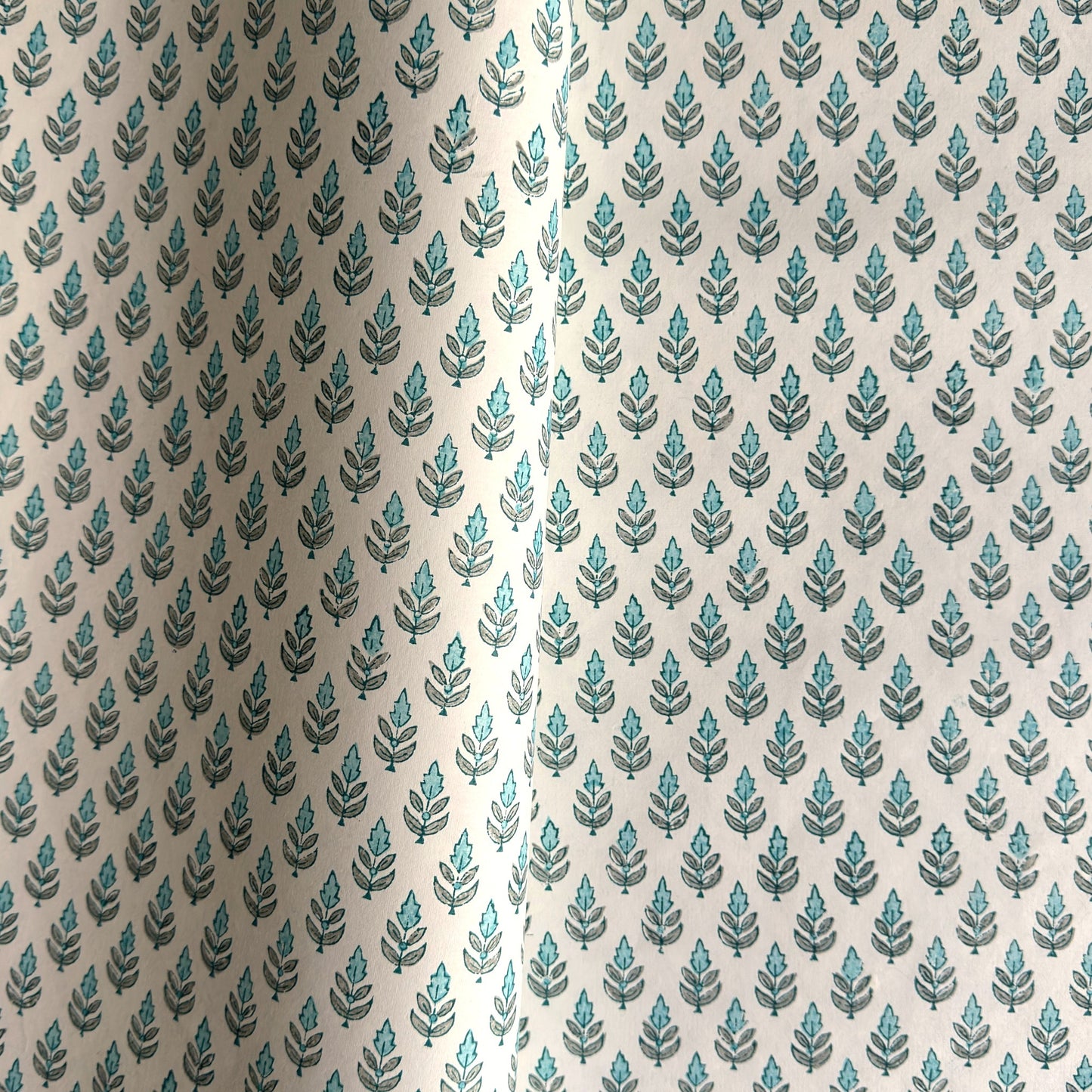 hand block printed wrapping paper by paper mirchi with a repeat floral pattern in turquoise and soft green on white backdrop
