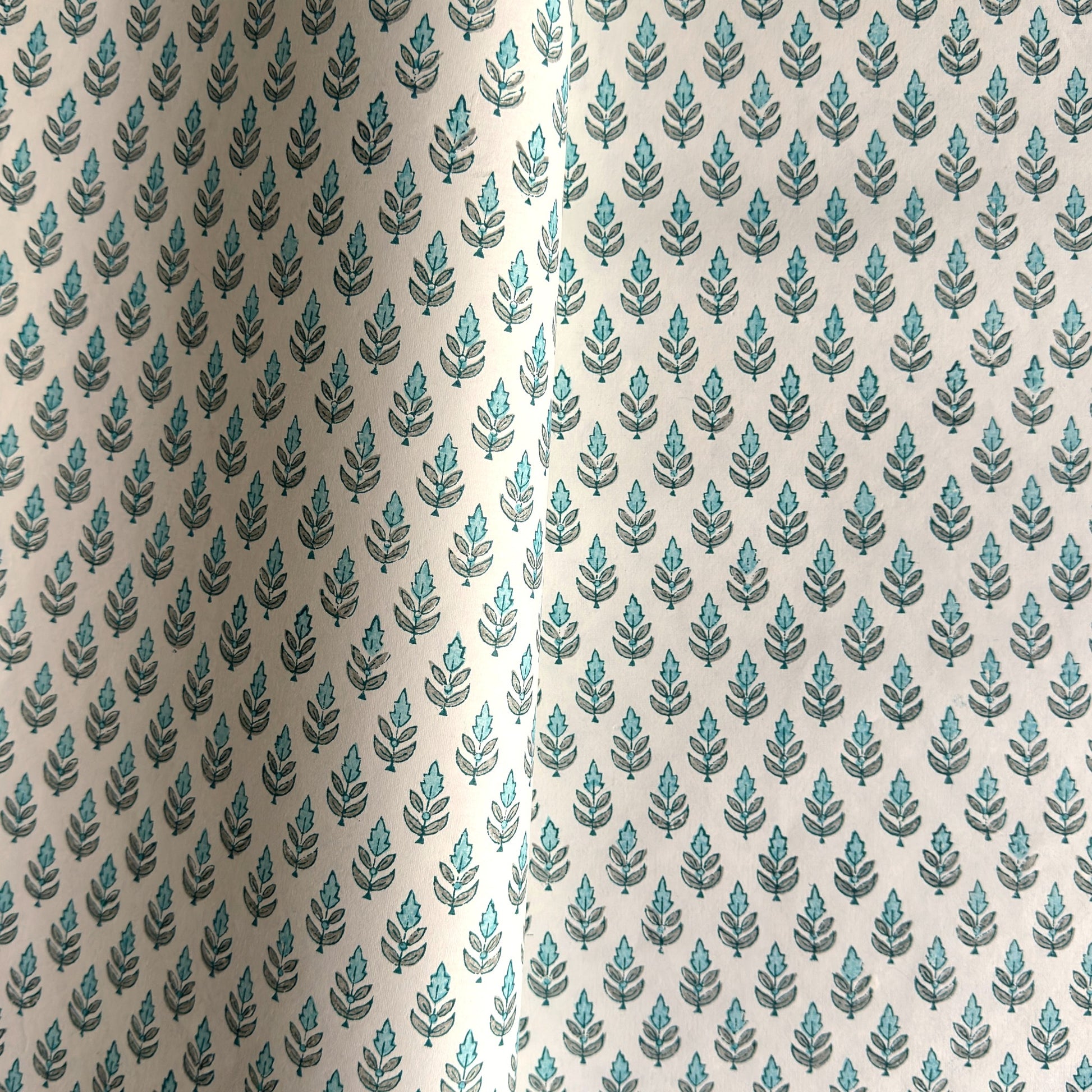 hand block printed wrapping paper by paper mirchi with a repeat floral pattern in turquoise and soft green on white backdrop