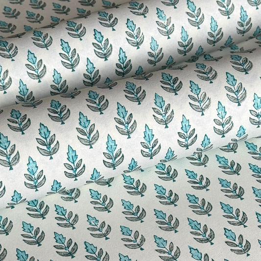 hand block printed wrapping paper by paper mirchi with a repeat floral pattern in turquoise and soft green on white backdrop. close up
