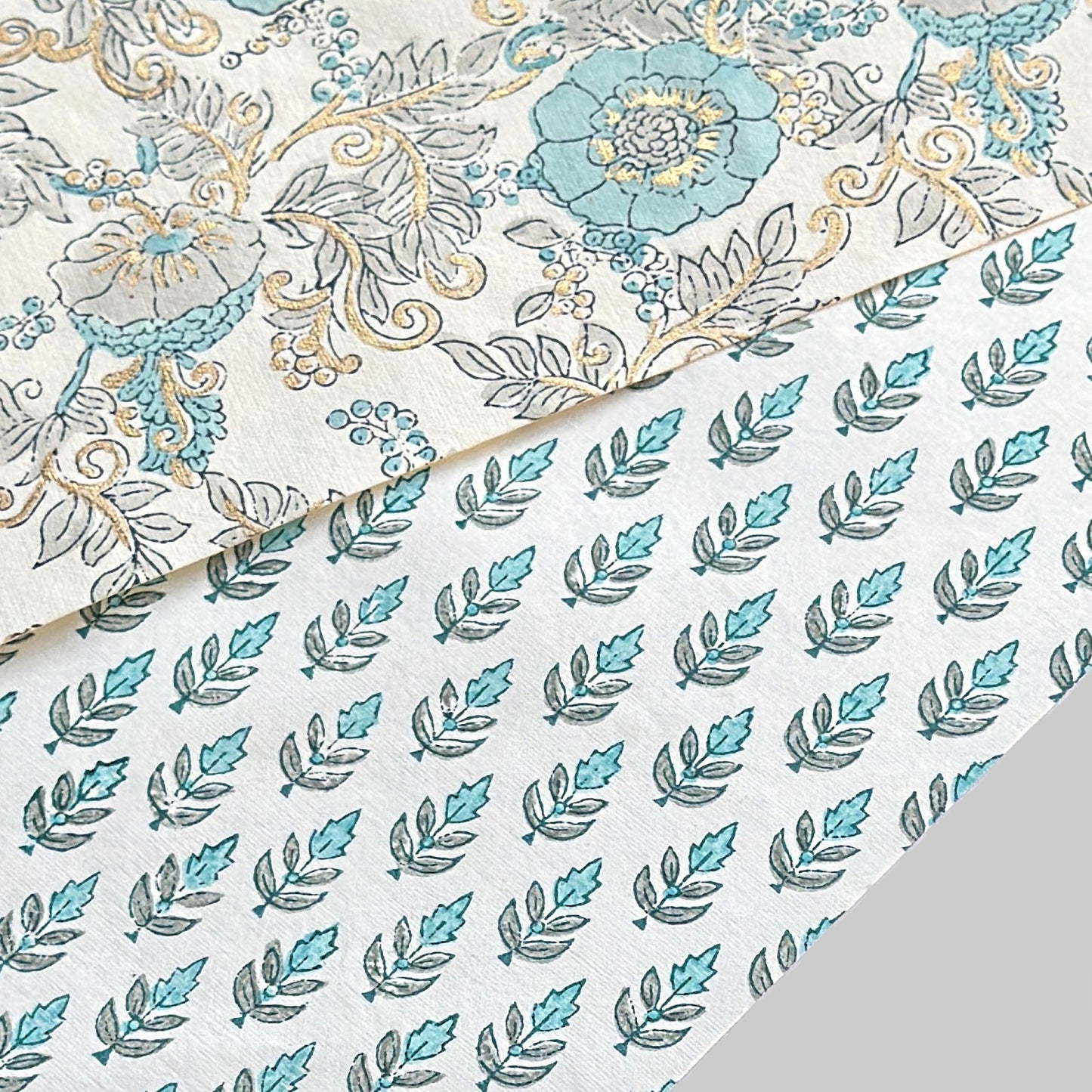 hand block printed wrapping paper by paper mirchi with a repeat floral pattern in turquoise and soft green on white backdrop