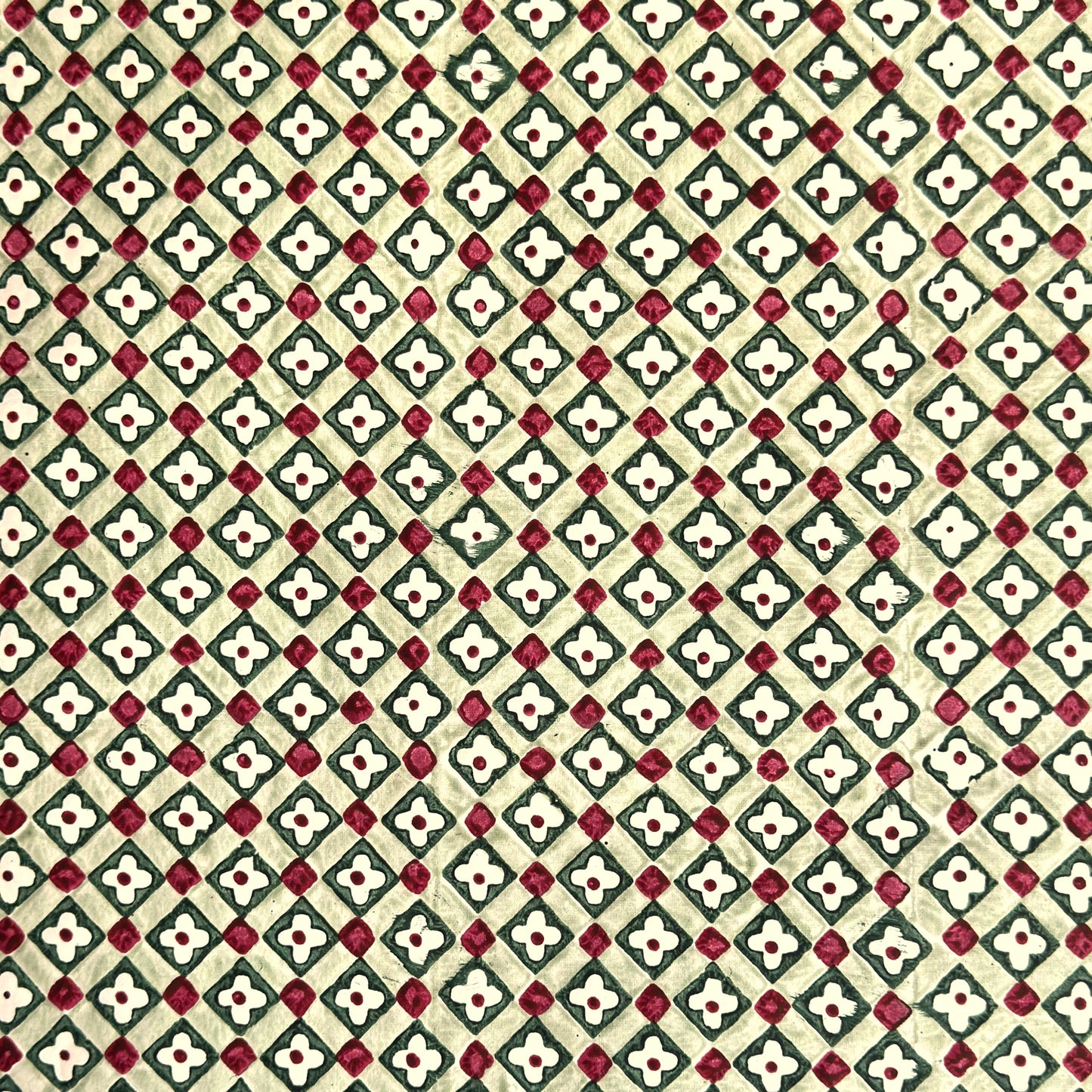 Hand block printed wrapping paper with a floral checked pattern in sage green and red.