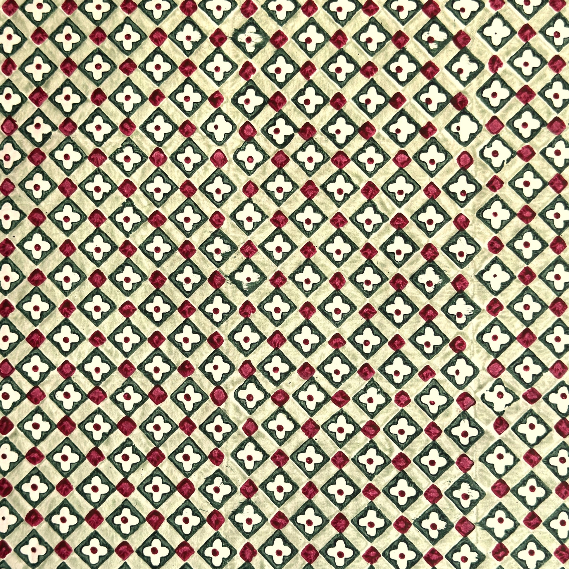 Hand block printed wrapping paper with a floral checked pattern in sage green and red.