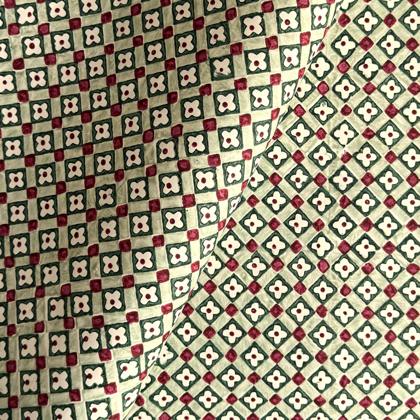 Hand block printed wrapping paper with a floral checked pattern in sage green and red.