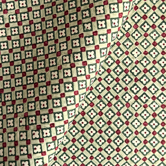 Hand block printed wrapping paper with a floral checked pattern in sage green and red.