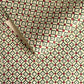 Hand block printed wrapping paper with a floral checked pattern in sage green and red.