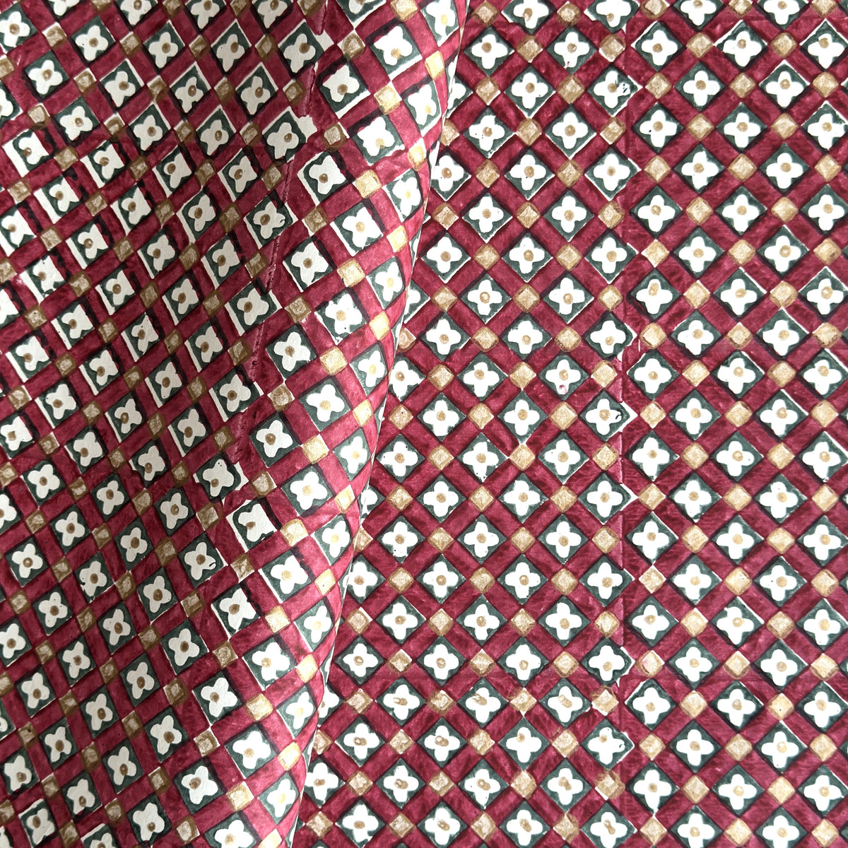 Hand block printed wrapping paper with a floral checked pattern in red, green and gold.