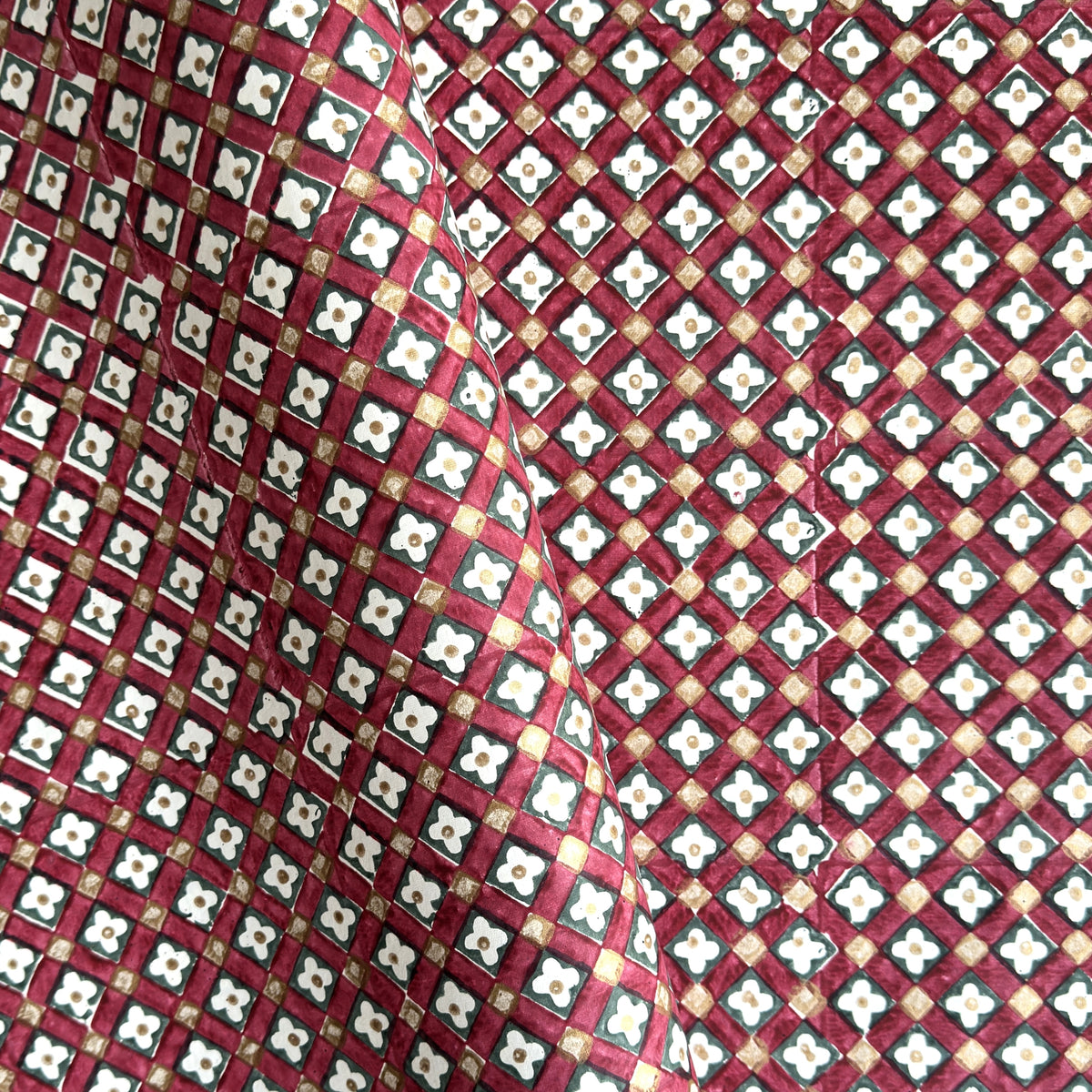 Hand block printed wrapping paper with a floral checked pattern in red, green and gold.