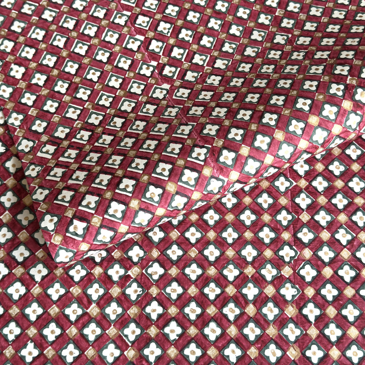 Hand block printed wrapping paper with a floral checked pattern in red, green and gold.