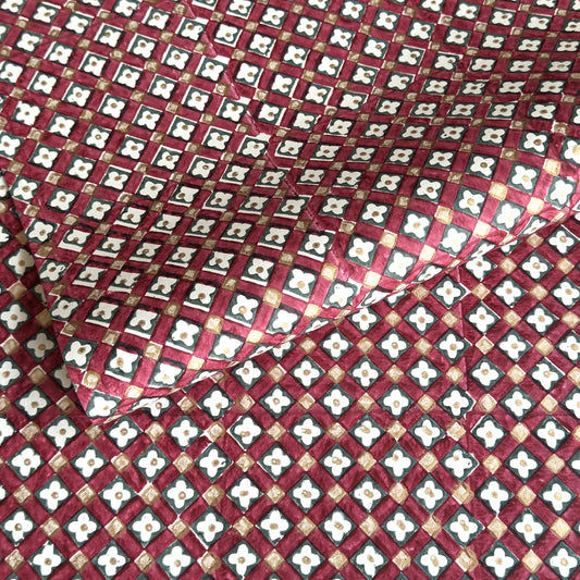 Hand block printed wrapping paper with a floral checked pattern in red, green and gold.