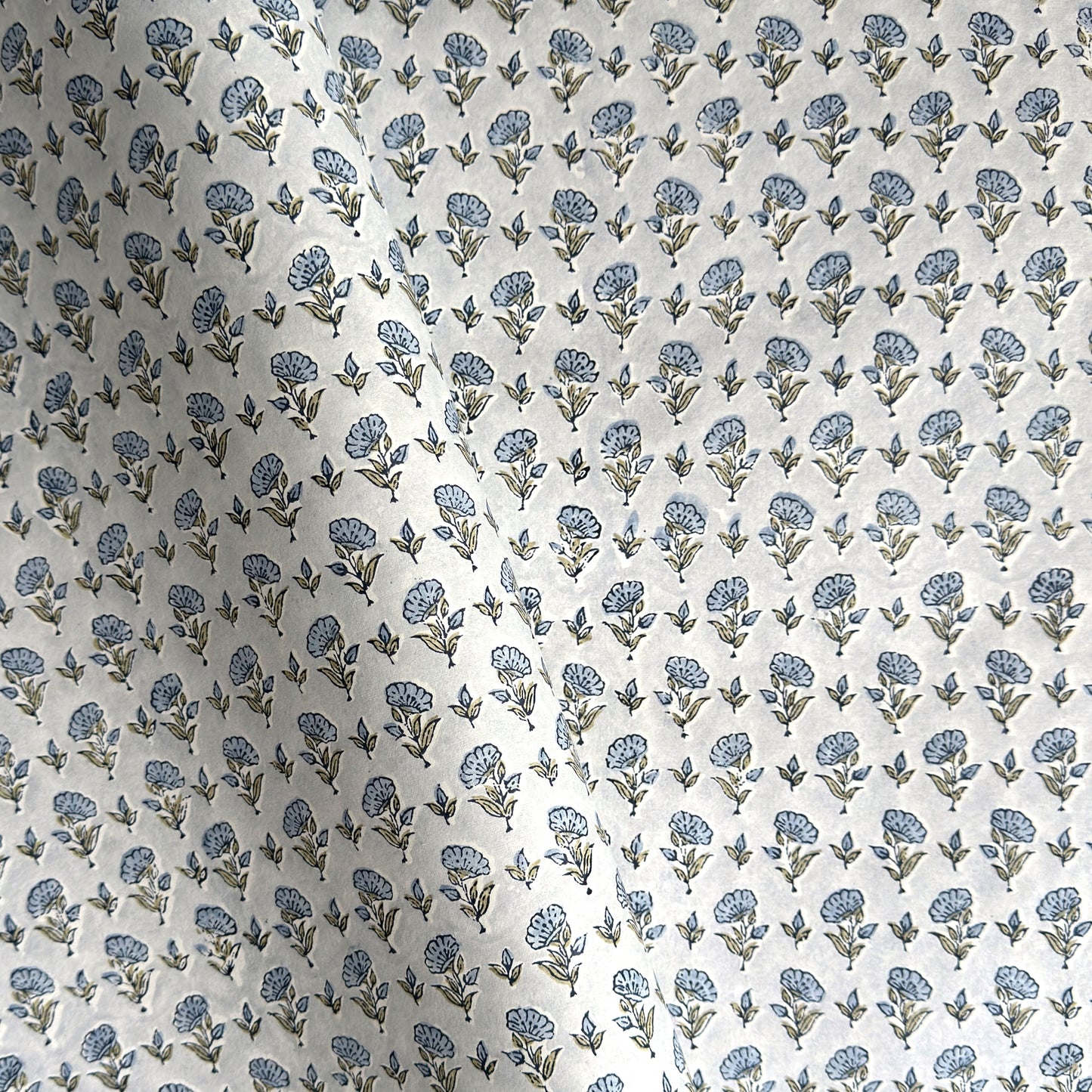 a hand block printed sheet of wrapping paper with a ditsy floral print in soft blue