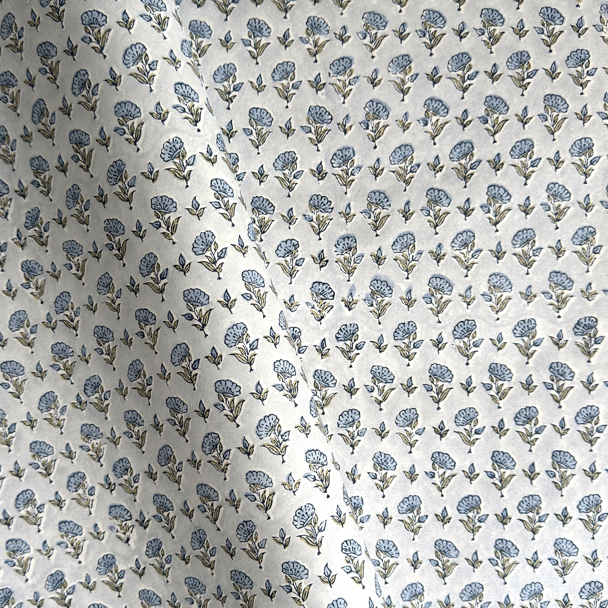 a hand block printed sheet of wrapping paper with a ditsy floral print in soft blue