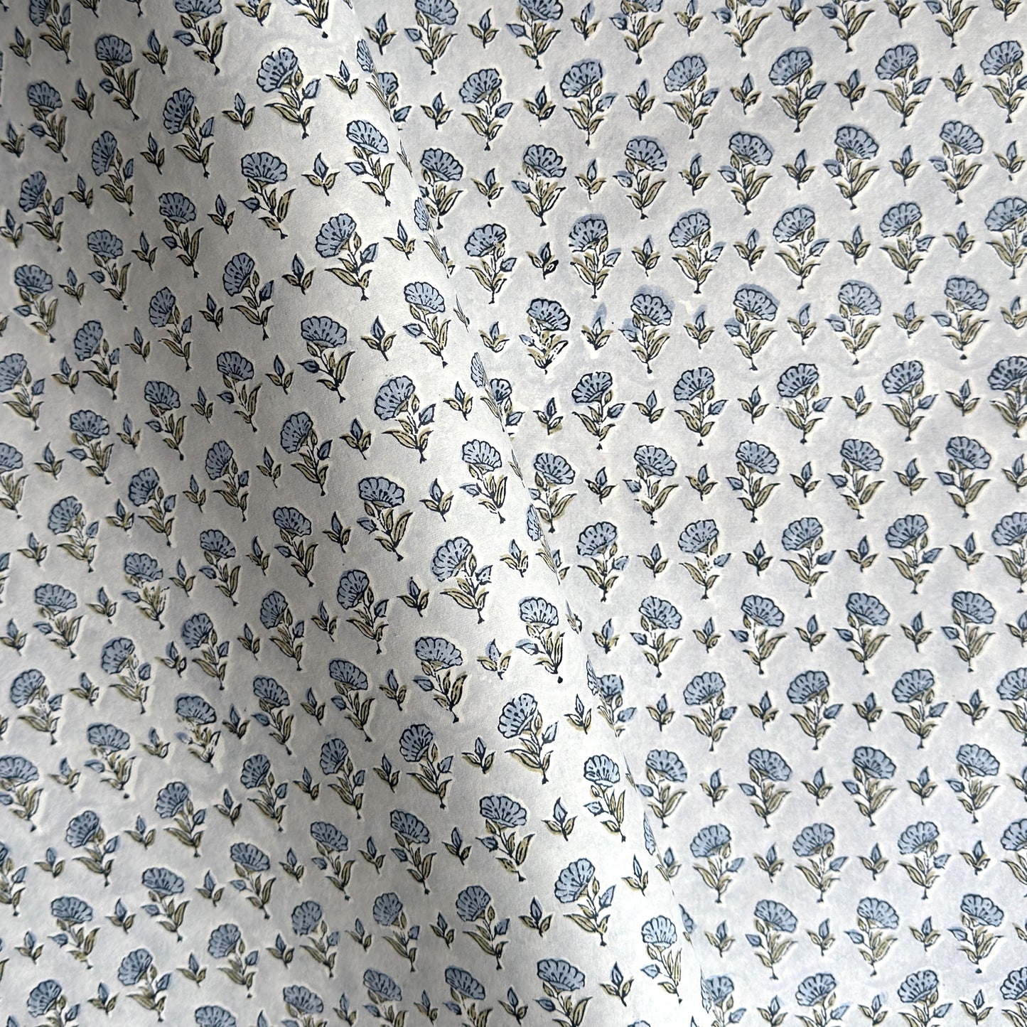 a hand block printed sheet of wrapping paper with a ditsy floral print in soft blue