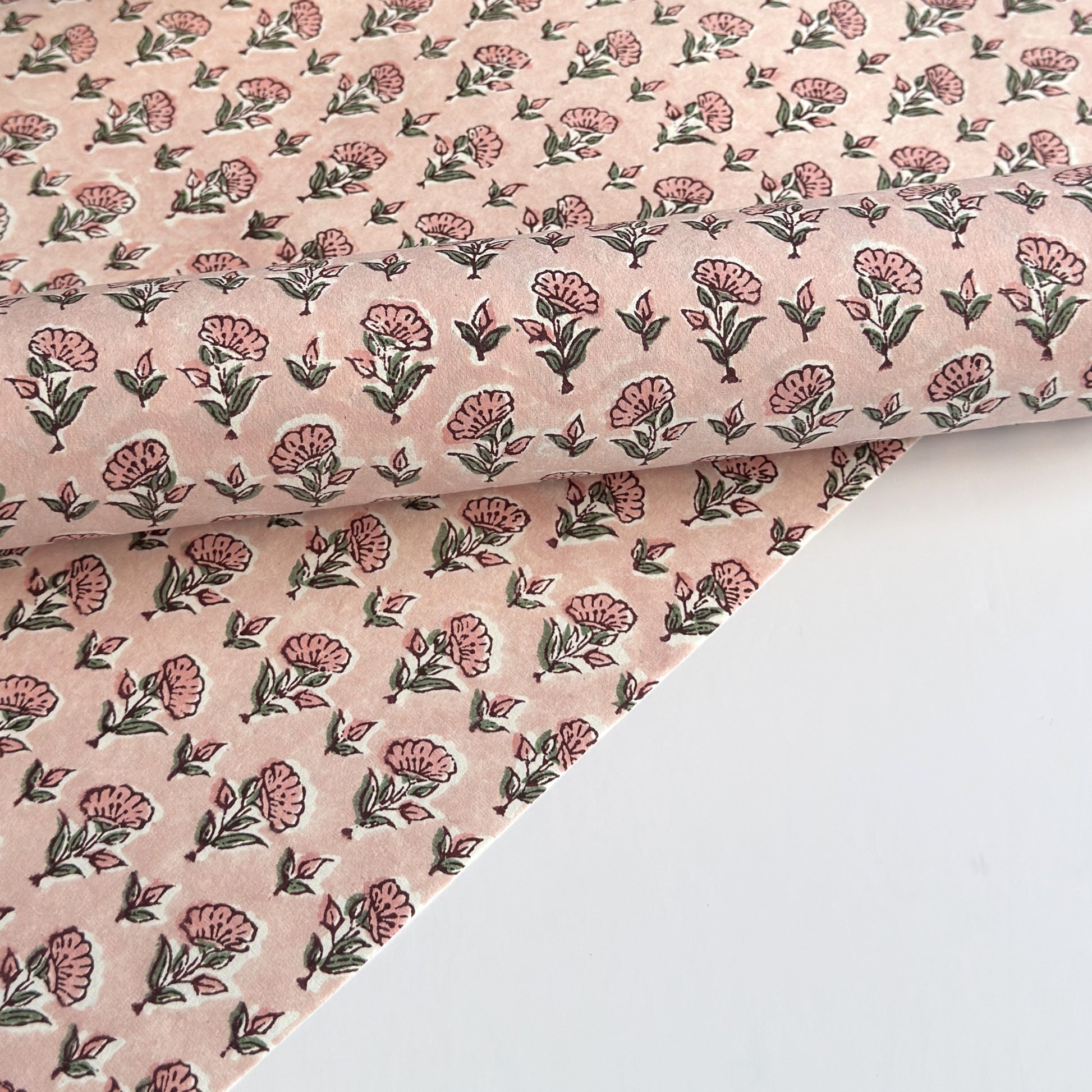 a hand block printed sheet of wrapping paper with a ditsy floral print in pink