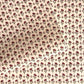 a sheet of hand block printed paper with a ditsy floral design in red and green on pink background