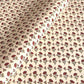 a sheet of hand block printed paper with a ditsy floral design in red and green on pink background