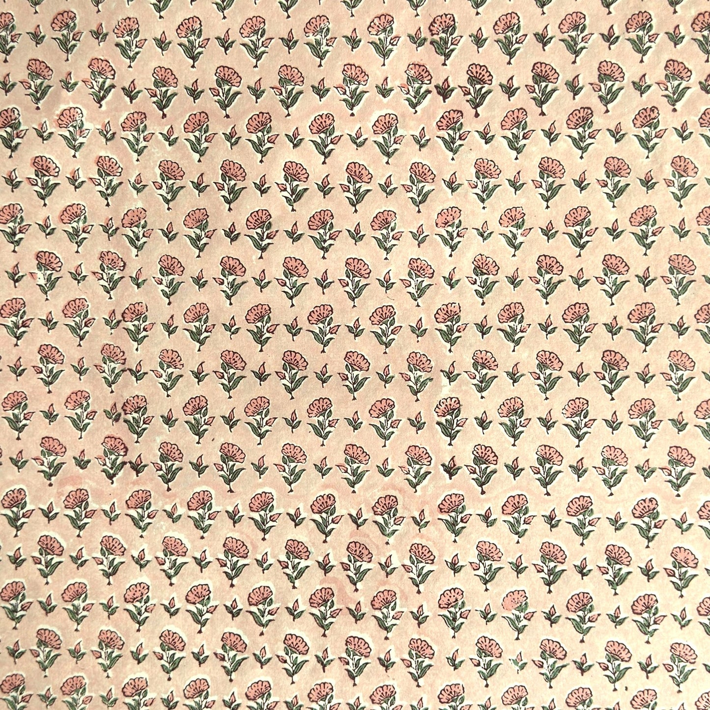a hand block printed sheet of wrapping paper with a ditsy floral print in pink. Pictured rolled with another design